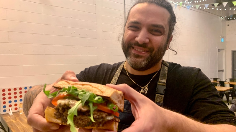 Adriano Ciotoli, co-owner of Windsor Eats holds up the restaurant’s newest creation, ‘The Burger Verde,’ on Feb. 2, 2023. (Rich Garton/CTV News Windsor)