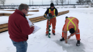 Chad Davis (left) writes down the ice thickness on the downtown Brockville rink a Dan Elwood (right) and Spencer Utman work on the rink. (Nate Vandermeer/CTV News Ottawa)