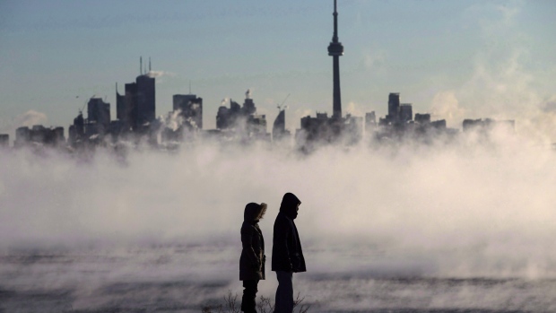 Steam rises as people look out on Lake Ontario in front of the skyline during extreme cold weather in Toronto. THE CANADIAN PRESS/Mark Blinch