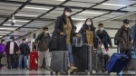 Travellers wearing face masks with their luggage head to the immigration counter at the departure hall at Lok Ma Chau station following the reopening of crossing border with mainland China, in Hong Kong, Sunday, Jan. 8, 2023. (AP Photo/Bertha Wang, File)