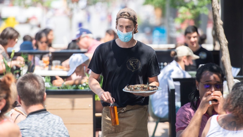 A server brings an order to a customer at a restaurant in Montreal, Sunday, June 6, 2021, as the COVID-19 pandemic continues in Canada and around the world. THE CANADIAN PRESS/Graham Hughes