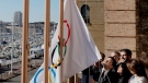 Mayor of Marseille Benoit Payan, centre, raises the Olympic flag with Head of Paris 2024 Olympics Tony Estanguet, centre right, after a press conference in southern France, Friday, Feb. 3. 2023. (AP Photo/Thibault Camus)