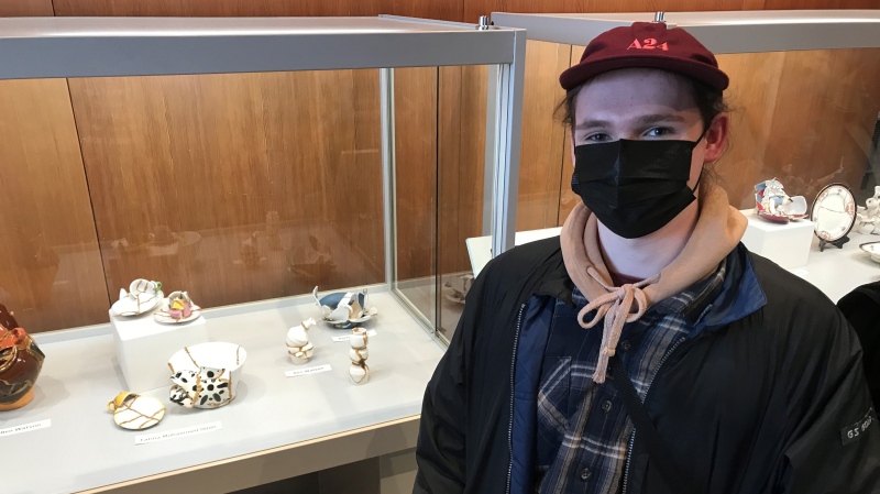 Ben Watson, a Grade 12 student at Forest Heights Collegiate Institute in Kitchener, stands beside his sculpture that's part of the 'Ceramic Stories Revisited' exhibit at the Canadian Clay & Glass Gallery.(Dan Lauckner/CTV Kitchener)