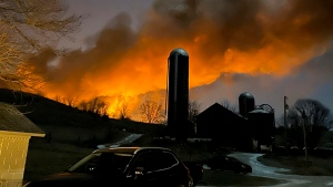 In this photo provided by Melissa Smith, a train fire is seen from her farm in East Palestine, Ohio, Friday, Feb. 3, 2023. A train derailment and resulting large fire prompted an evacuation order in the Ohio village near the Pennsylvania state line on Friday night, covering the area in billows of smoke lit orange by the flames below. (Melissa Smith via AP)