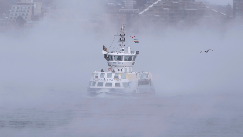 Passengers stand on the open deck while riding a ferry across Halifax Harbour as sea smoke, or ice fog, forms in Halifax on Saturday, February 4, 2023. Environment Canada has warned of windchill values between -30 C and -40 C across the Maritimes as an Arctic air mass moves across the region. THE CANADIAN PRESS/Darren Calabrese