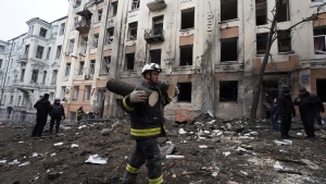An emergency worker carries pieces of a sawn tree in front of a residential building which was hit by a Russian rocket at the city center of Kharkiv, Ukraine, Sunday, Feb. 5, 2023. (AP Photo/Andrii Marienko) 