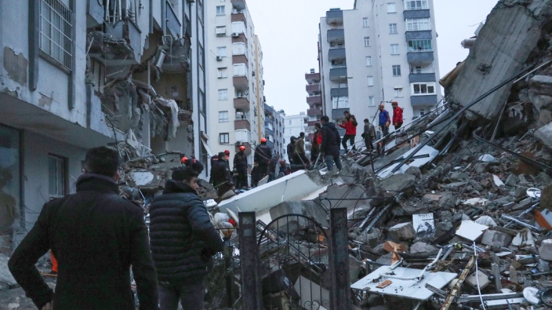 People and rescue teams try to reach trapped residents inside collapsed buildings in Adana, Turkey, Feb. 6, 2023. A powerful quake has knocked down multiple buildings in southeast Turkey and Syria and many casualties are feared. (IHA agency via AP)