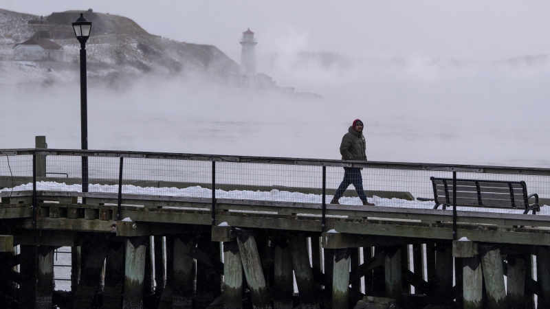 A man walks on the waterfront as sea smoke, or ice fog, forms in Halifax Harbour on Saturday, February 4, 2023. THE CANADIAN PRESS/Darren Calabrese