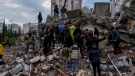 People and emergency teams search for people in a destroyed building in Adana, Turkiye, Monday, Feb. 6, 2023. (AP Photo/Khalil Hamra)