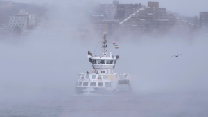 Passengers stand on the open deck while riding a ferry across Halifax Harbour as sea smoke, or ice fog, forms in Halifax on Saturday, February 4, 2023. (THE CANADIAN PRESS/Darren Calabrese)