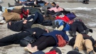 An image of protesters laying on the icy ground at Nathan Phillips Square, dramatizing sleeping on the street. (CTV News Toronto)