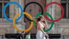 A woman passes by the Olympic rings at the City Hall in Paris, on July 25, 2022. (AP Photo/Lewis Joly, File)