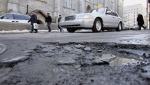 Motorists steer past a pothole on a Montreal street. FILE PHOTO - THE CANADIAN PRESS/Paul Chiasson