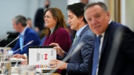 Prime Minister Justin Trudeau flips open a briefing book titled 'Working Meeting of First Ministers On Health Care' as he meets with Canada's premiers in Ottawa on Tuesday, Feb. 7, 2023 in Ottawa. Manitoba Premier Heather Stefanson sits to his right and Quebec Premier Francois Legault to his left. THE CANADIAN PRESS/Sean Kilpatrick