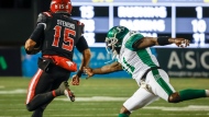 Saskatchewan Roughriders' Larry Dean, right, reaches for Calgary Stampeders' quarterback Tommy Stevens as he runs the ball for a touchdown during first half CFL football action in Calgary, Saturday, Oct. 29, 2022.THE CANADIAN PRESS/Jeff McIntosh 