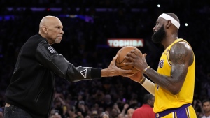 Kareem Abdul-Jabbar, left, hands the ball to Los Angeles Lakers forward LeBron James after James passed Abdul-Jabbar to become the NBA's all-time leading scorer during an NBA game against the Oklahoma City Thunder, Feb. 7, 2023, in Los Angeles. (AP Photo/Ashley Landis)