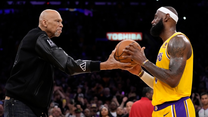 Kareem Abdul-Jabbar, left, hands the ball to Los Angeles Lakers forward LeBron James after passing Abdul-Jabbar to become the NBA's all-time leading scorer during the second half of an NBA basketball game against the Oklahoma City Thunder Tuesday, Feb. 7, 2023, in Los Angeles. (AP Photo/Ashley Landis)