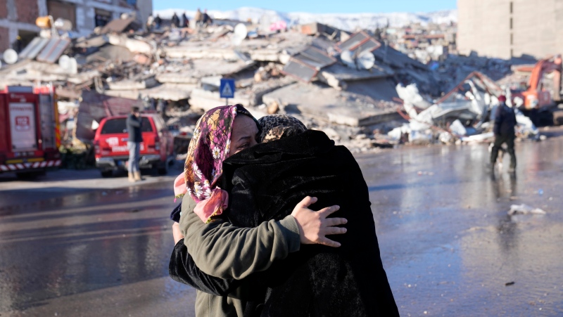 Two women hug each other in front of a destroyed building in Kahramanmaras, southern Turkiye, Wednesday, Feb. 8, 2023. (AP Photo/Hussein Malla)