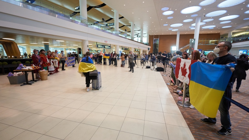 Natalie and Paul Lebedev hold Canadian and Ukrainian flags as they greet Ukrainian nationals fleeing the ongoing Russian invasion of Ukraine as they arrive in at the Richardson International Airport, in Winnipeg, Monday, May 23, 2022. THE CANADIAN PRESS/David Lipnowski