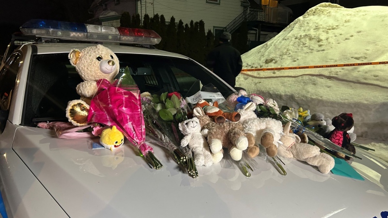 A makeshift memorial on a police cruiser remains at the scene of a deadly crash at a daycare in Laval, Que. on Wednesday, Feb. 8, 2023. Two children were killed and others were injured after a city bus crashed into the entrance of the daycare. (Olivia O'Malley/CTV News)