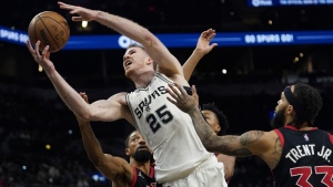 San Antonio Spurs centre Jakob Poeltl (25) drives to the basket against Toronto Raptors center Khem Birch (24) and guard Gary Trent Jr. (33) during the second half of an NBA basketball game Wednesday, March 9, 2022, in San Antonio. (AP Photo/Eric Gay)