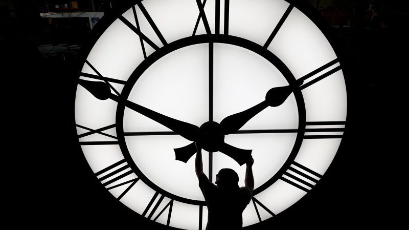 Electric Time technician Dan LaMoore adjusts a clock hand on a 1000-lb., 12-foot diameter clock constructed for a resort in Vietnam, Tuesday, March 9, 2021, in Medfield, Mass. (AP Photo/Elise Amendola)