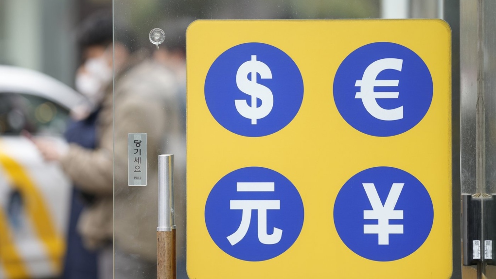 People walk near a sign of foreign currency 
