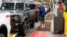 An assembly line worker looks over a 2021 Ford Bronco on the line at Michigan Assembly Plant, Monday, June 14, 2021, in Wayne, Mich. (AP Photo/Carlos Osorio)