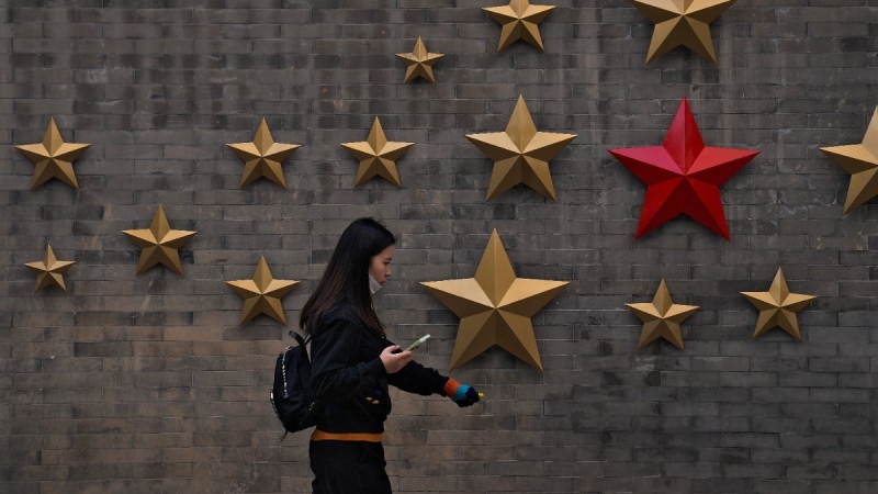 A woman walks by communist symbol of a star outside a restaurant in Beijing, on March 5, 2023. (Andy Wong / AP)