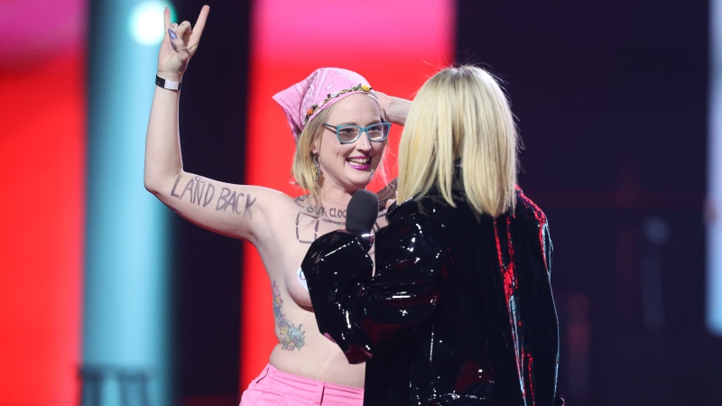 Avril Lavigne confronts a topless protester as she presents during the Junos Monday, March 13, 2023 (The Canadian Press/Timothy Matwey).