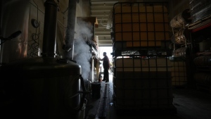 Scott Thompson, founder of Mad Laboratory Distilling, works to keep grains moving from a hopper as they are fed to a mash tank while steam rises from a still being cleaned at the distillery, in Vancouver, on March 9, 2023. Mad Lab switched to produce hand sanitizer during the pandemic but is now back to full-time production of alcoholic beverages. (THE CANADIAN PRESS/Darryl Dyck)