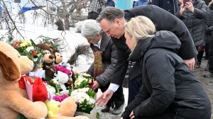 Quebec Premier Francois Legault sets flowers at a makeshift memorial for the victims, in Amqui, Que., Thursday, March 16, 2023. Legault is flanked by Amqui mayor Sylvie Blanchette, behind, and Quebec Minister of Natural Resources and Forests Maite Blanchette Vezina, front. THE CANADIAN PRESS/Jacques Boissinot