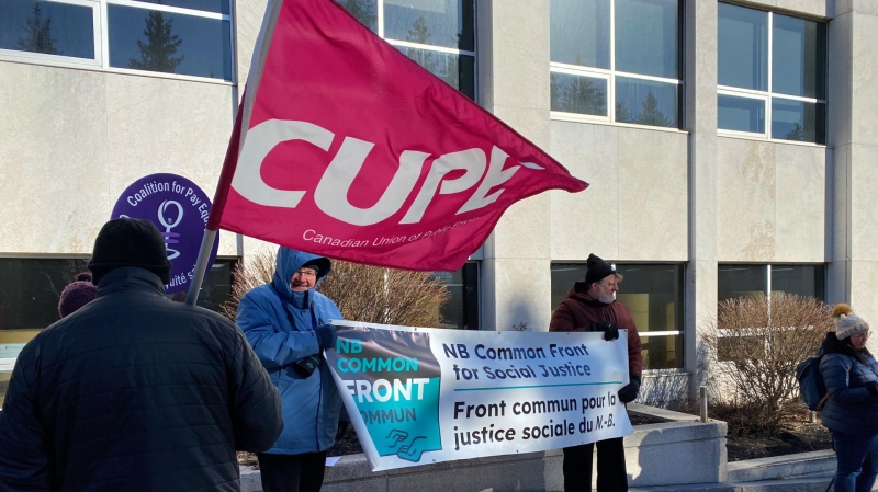 People with the NB Common Front for Social Justice rally outside the former Times and Transcript building in Moncton, N.B., on March 20, 2023, the day before the provincial budget is announced in Fredericton. The group planned the rally in hopes of bringing awareness to social and economic factors people in the province are struggling with every day. (Derek Haggett/CTV) 