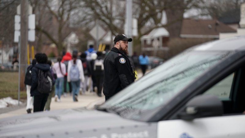 A police officer escorts students at the scene of a shooting at a high school in Toronto on February 16, 2023. THE CANADIAN PRESS/Arlyn McAdorey