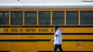 A Los Angeles Unified School District bus driver walks past parked vehicles at a bus garage in Gardena, Calif., on Dec. 15, 2015. (AP Photo/Damian Dovarganes, File)