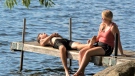 A couple relaxes on a dock on Pigeon Lake near Bobcaygeon, Ont., Friday, July 19, 2019. THE CANADIAN PRESS/Fred Thornhill