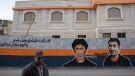 A man walks past a mural that depicts two local Palestinians who were killed during clashes with Israeli army soldiers, Saji Darwish in 2014, right and Rabeh Hamed in 1988 and reads, 'You were our smiling spectrum and today you move on and leave a trace in our life,' in their West Bank home village of Betin, near Ramallah, Tuesday, March 21, 2023. (AP Photo/Nasser Nasser) 