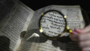 A member of staff shows the Hebrew Bible 'Codex Sassoon,' that dates back more than 1,000 years, on display during a media preview of Sotheby's auction, in London, Feb. 22, 2023.  (AP Photo/Kin Cheung)