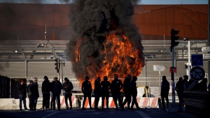 Dock workers stand in front of a burning barricade next the port of Marseille southern France, Wednesday, March 22, 2023. (AP Photo/Daniel Cole) 