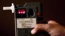 An officer holds a breathalyzer device in this file photo. (The Canadian Press/Darryl Dyck)