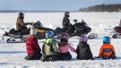 Children watch family day weekend snowmobile radar runs on Sturgeon Lake in the city of Kawartha Lakes, Ont., Sunday, Feb. 20, 2022. THE CANADIAN PRESS/Fred Thornhill