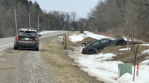 A black car is seen in the ditch near the corner of Wellington Road 18 and Fourth Line in Centre Wellington on March 22, 2023. (Dan Lauckner/CTV Kitchener)
