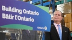 Ontario Finance Minister Peter Bethlenfalvy listens to Ontario Premier Doug Ford speak after touring the Oakville Stamping and Bending Limited facility in Oakville, Ont., on Wednesday, March 22, 2023. THE CANADIAN PRESS/Nathan Denette 
