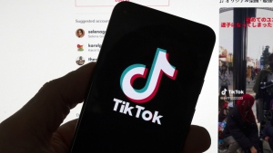 The TikTok logo is seen on a mobile phone in front of a computer screen which displays the TikTok home screen, Saturday, March 18, 2023, in Boston. (AP Photo/Michael Dwyer, File)