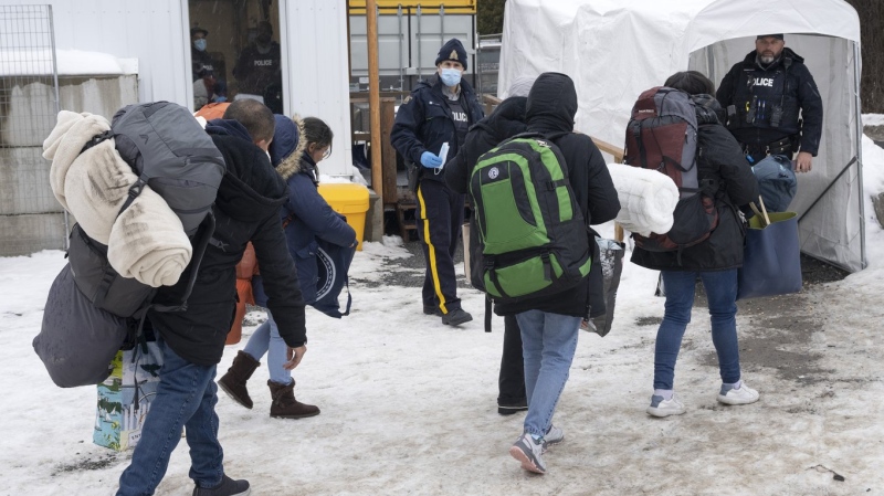 A family of asylum seekers from Colombia is met by RCMP officers after crossing the border at Roxham Road into Canada Thursday, February 9, 2023 in Champlain, New York. Canada and the United States are on the cusp of agreeing to designate all 8,900 km of their shared border as an official crossing under the Safe Third Country Agreement. THE CANADIAN PRESS/Ryan Remiorz