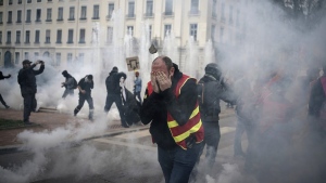 Protesters run amid the tear gas during a demonstration in Lyon, central France, March 23, 2023. (AP Photo/Laurent Cipriani)