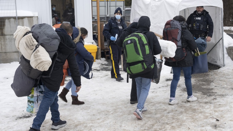 A family of asylum seekers from Colombia is met by RCMP officers after crossing the border at Roxham Road into Canada, Feb. 9, 2023 in Champlain, New York. THE CANADIAN PRESS/Ryan Remiorz