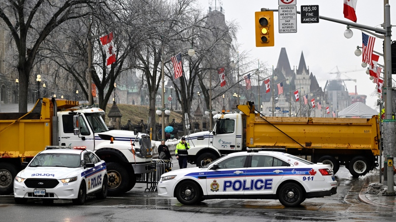 Police vehicles and dump trucks control access to Wellington Street in front of Parliament Hill in Ottawa, before the visit of U.S. President Joe Biden to Canada, on Thursday, March 23, 2023. THE CANADIAN PRESS/Justin Tang