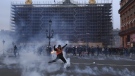 A protester kicks a tear gas canister in front of the Opera at the end of a rally in Paris, Thursday, march 23, 2023. (AP Photo/Aurelien Morissard)