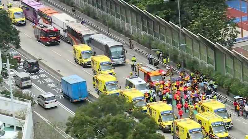 In this image taken from a video footage run by TVB, rescue workers attend to the aftermath after four passenger buses and a truck collided near a Hong Kong road tunnel Friday, March 24, 2023. Dozens were injured, including children. Most of the injuries were minor. (TVB via AP) 